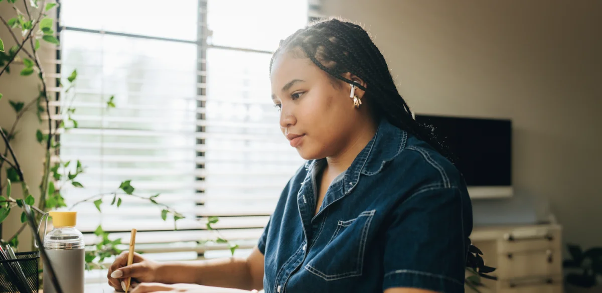 Student taking notes while attending to an online class