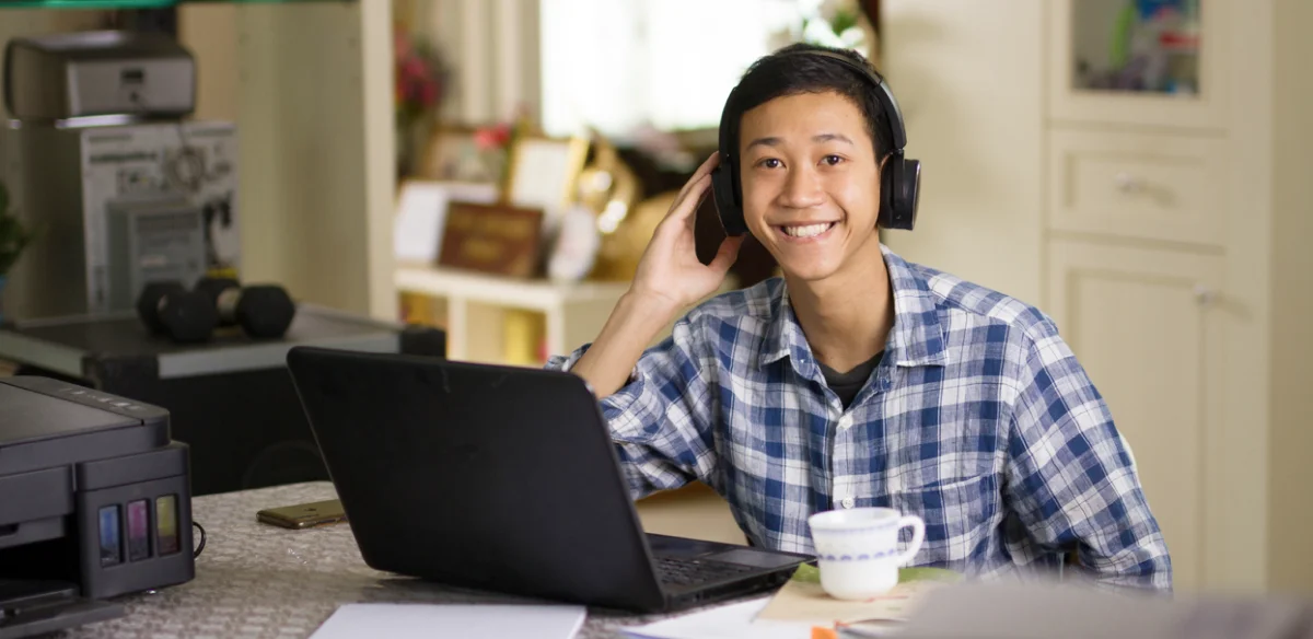 Student attending to an online class at home wearing a black pair of headphones