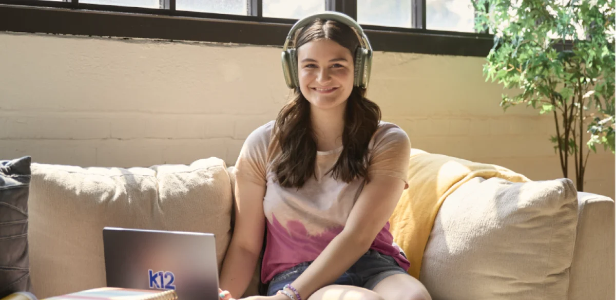 Student attending to an online class wearing a light green pair of headphones