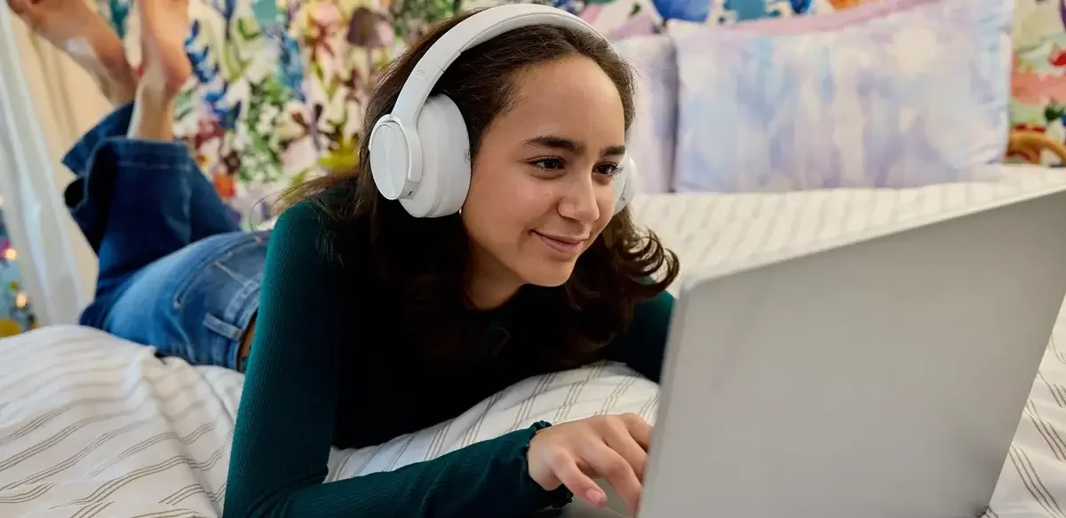 Student attending to an online class wearing a white pair of headphones
