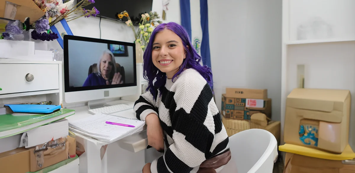 High school student attending to an online class at home wearing a stripped sweater